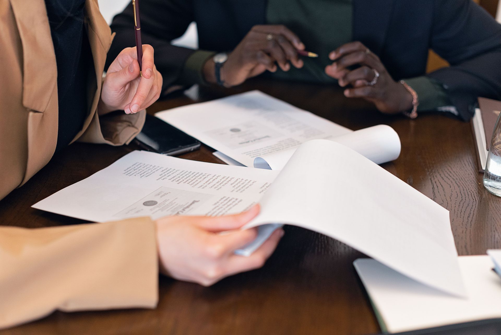 Close-up of professionals reviewing documents during a business meeting in an office setting.